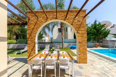 a patio with a table and chairs and a pool at Ayia Napa Ionion Seaside Villa in Ayia Napa