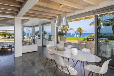 a dining room with a table and chairs and the ocean at Beachfront Dream Villa in Protaras