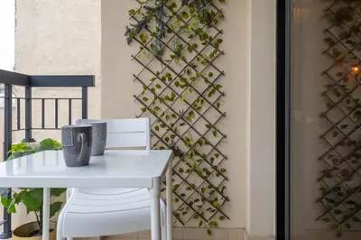 a white table and chairs next to a wall with ivy at Johny's Spot in Larnaca in Larnaka