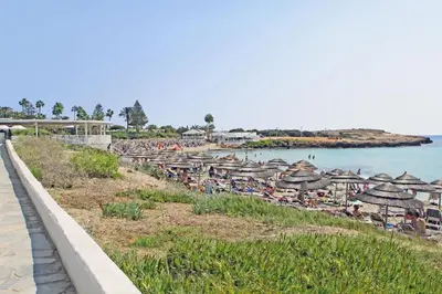 a beach with umbrellas and people sitting on the beach at Villa Nissinia - Nissi Beach Area in Ayia Napa