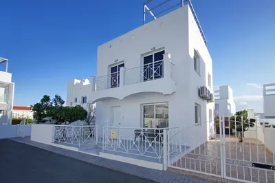 a white building with tables on the balcony at Villa Nissinia - Nissi Beach Area in Ayia Napa
