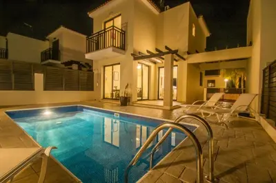 a swimming pool in front of a house at night at Protaras Allium Villa in Protaras