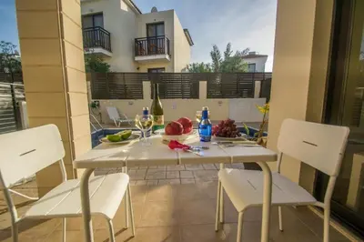 a white table with white chairs and wine glasses on it at Protaras Allium Villa in Protaras