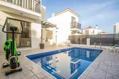 a swimming pool with a lawn mower next to a house at Protaras Allium Villa in Protaras