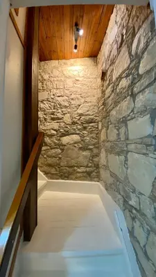 a bath tub in a room with a stone wall at Leonys House by TrulyCyprus in Doros