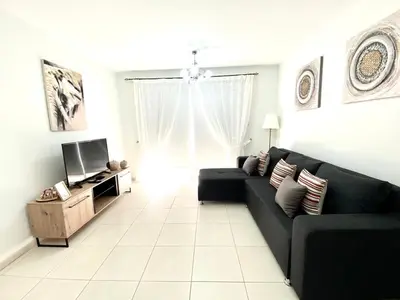 a living room with a black couch and a television at NISSI 3 VIEW HOLIDAY 2 BEDROOM APARTMENT in Ayia Napa