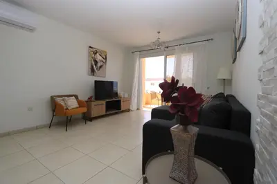 a living room with a black couch and a tv at NISSI 3 VIEW HOLIDAY 2 BEDROOM APARTMENT in Ayia Napa