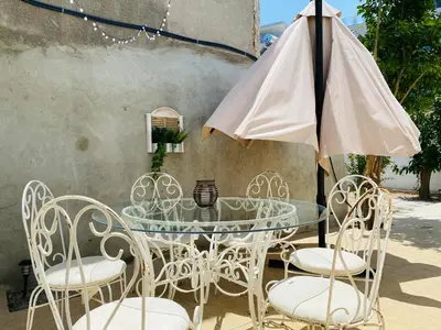 a glass table with chairs and an umbrella at Serena's 2-BR Apartment in Larnaca in Larnaka