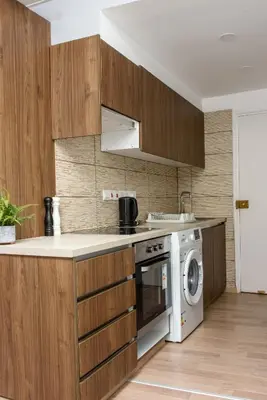 a kitchen with wooden cabinets and a washing machine at Valdivian Flat 18 in Larnaka