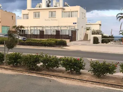 a building on the side of a road with bushes at Sunny holiday by konnos in Paralimni