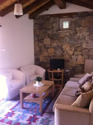 a living room with couches and a table and a tv at Maison Elena in Kalopanayiotis