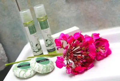 a white table with pink flowers and two bottles of soap at Agrovino Lofou in Lofou