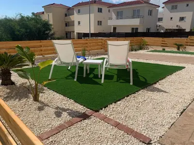 two chairs and a table on a patch of grass at Nissi3 B1 Lovely 1Bdr Ground Floor Apartment near Nissi Beach. in Ayia Napa