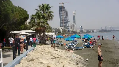 a group of people on a beach with blue umbrellas at Antonakis 501 in Limassol