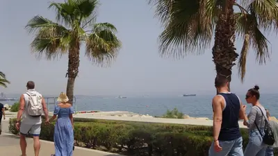 a group of people walking on a sidewalk near the water at Antonakis 501 in Limassol