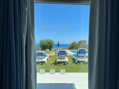 a view of chairs and a pool from a window at Ocean Suites Luxury Apartments in Protaras