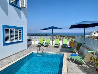 a swimming pool with chairs and umbrellas on a balcony at Villa Kapparis Sunrise in Paralimni