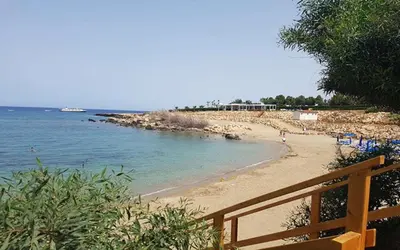 a beach with a wooden fence and the ocean at Villa Queen Valeria in Protaras