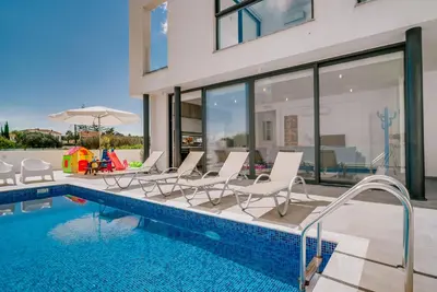 a swimming pool with lounge chairs and a house at SunnyVillas: 2BR New Villa☆Private Pool in Pernera - Nicholas in Protaras