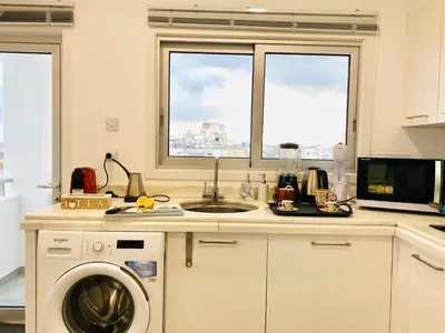 a kitchen with a sink and a washing machine at Panoramic Seaside Getaway, 2-BR Penthouse in Larnaka