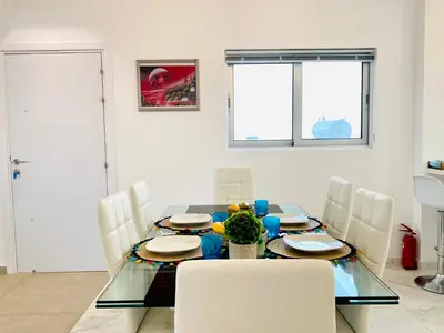 a dining room with a glass table and white chairs at Panoramic Seaside Getaway, 2-BR Penthouse in Larnaka