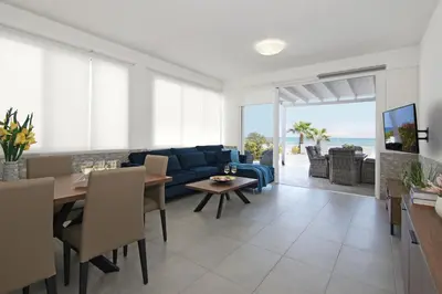 a living room with a blue couch and a table at Villa Aphrodisia - Seafront in Ayia Napa