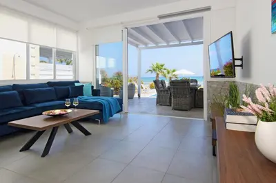 a living room with a blue couch and a table at Villa Aphrodisia - Seafront in Ayia Napa