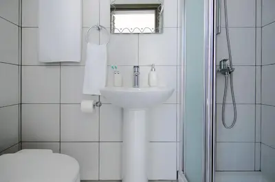 a white bathroom with a sink and a shower at Villa Aphrodisia - Seafront in Ayia Napa