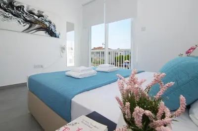 a bedroom with a blue and white bed and a plant at Villa Aphrodisia - Seafront in Ayia Napa