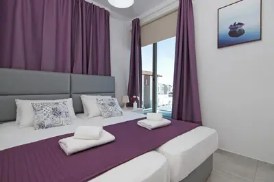 a bedroom with a large bed with purple curtains at Villa Levandini in Protaras