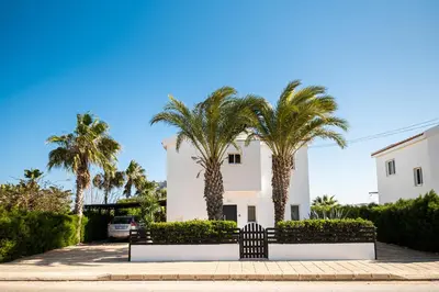 a white building with palm trees in front of it at Protaras View Villas in Protaras