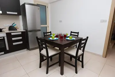 a kitchen with a wooden table with chairs and drinks at Pernera Holiday Villa 588 in Paralimni