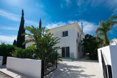 a white house with trees and a fence at Villa Helena in Ayia Napa