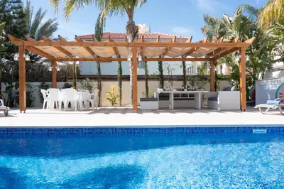 a pool with a pergola and a table and chairs at Villa Helena in Ayia Napa