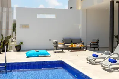 a swimming pool with chairs and a table and a pool at Protaras Almaria Villa 16 in Protaras