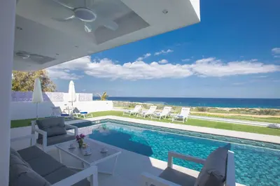 a swimming pool with chairs and a view of the ocean at Artizan Seafront Villa 5 in Protaras