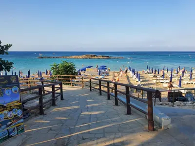 a beach with chairs and umbrellas and the ocean at Villa - Sleeps 6 free parking & heated pool in Protaras