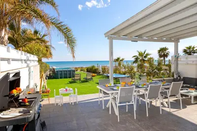 a patio with a table and chairs and the ocean at Ayia Thekla Seafront Villa Dagi in Ayia Napa