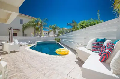 a backyard with a swimming pool and a white house at Kalamies Family Villa in Protaras