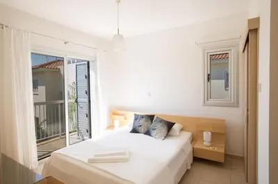a white bedroom with a bed and a large window at Kalamies Family Villa in Protaras