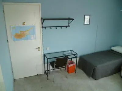 a bedroom with a bed and a desk and a door at Datacom House - The Sky Blue Room in Nicosia