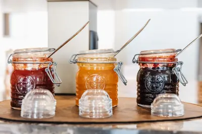 four jars of honey on a wooden shelf at Limassol Del Mar in Limassol