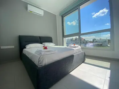 a bedroom with a large bed with a large window at Stay in Style in Modern 3 Bedroom Villas Near Nissi Beach & Square in Ayia Napa