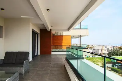 a balcony with a chair and glass railing at Phaedrus Living: Sea View Anna Residence 201 in Limassol