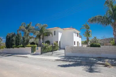 a white house with palm trees and a fence at Villa Margarita in Protaras