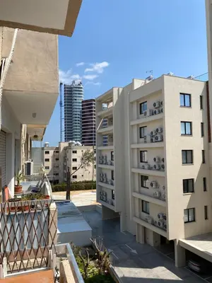 a white apartment building with buildings in the background at 1 bedroom flat 200m from the beach in germasogia tourist area in Limassol