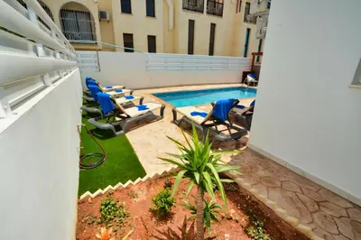 a pool with lounge chairs next to a building at Nissi Villa Sotia in Ayia Napa