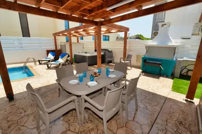 a patio with a table and chairs and a grill at Nissi Villa Sotia in Ayia Napa