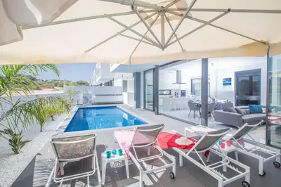 an outdoor patio with a swimming pool and chairs and a table at Anassa Seaview Villa - Stunning Panoramic Views in Protaras