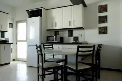 a kitchen with a table and chairs and a refrigerator at MAMA'S FLAT - ΤΟ ΔΙΑΜΕΡΙΣΜΑ ΤΗΣ ΜΑΜΑΣ in Strovolos